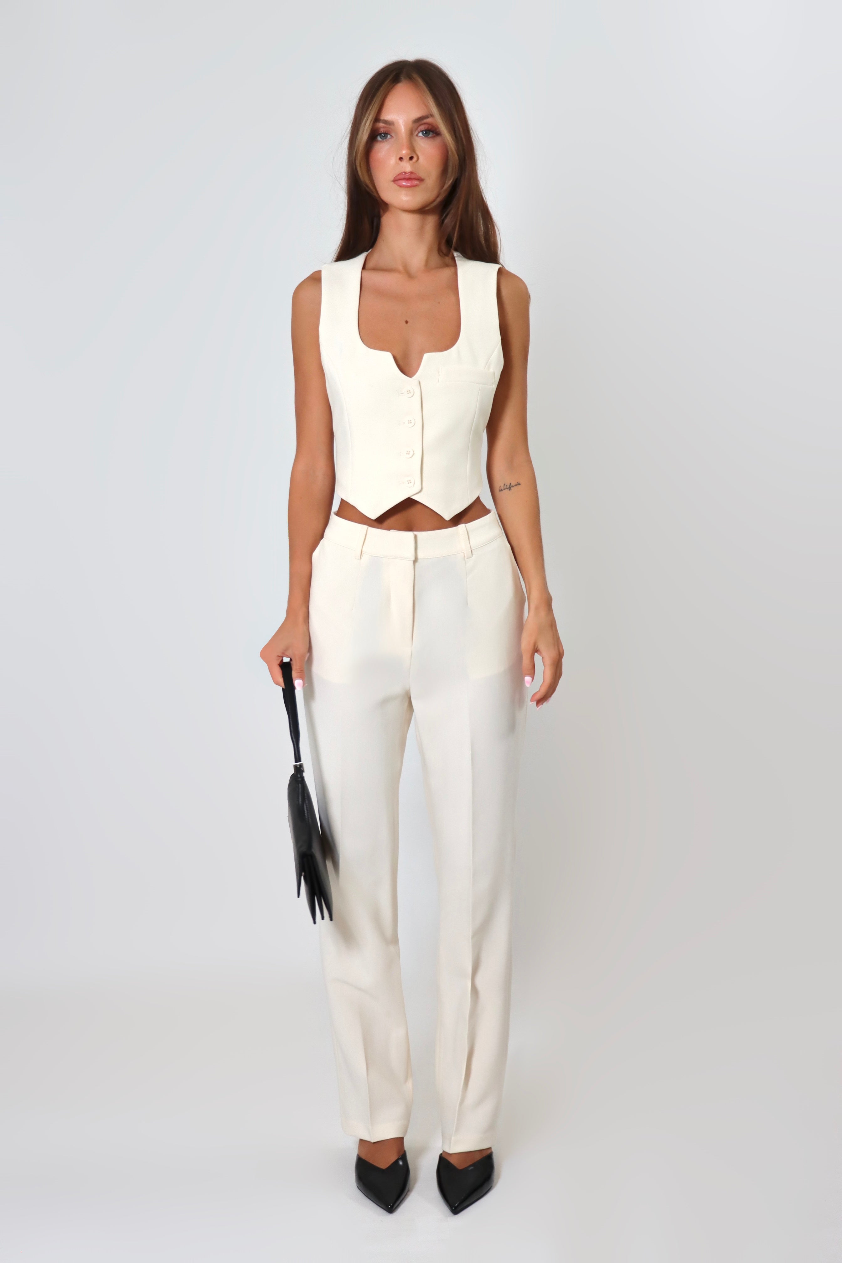 April Seven cropped backless vest and straight-leg pant set in white – minimalist tailored two-piece with clasp-back vest.