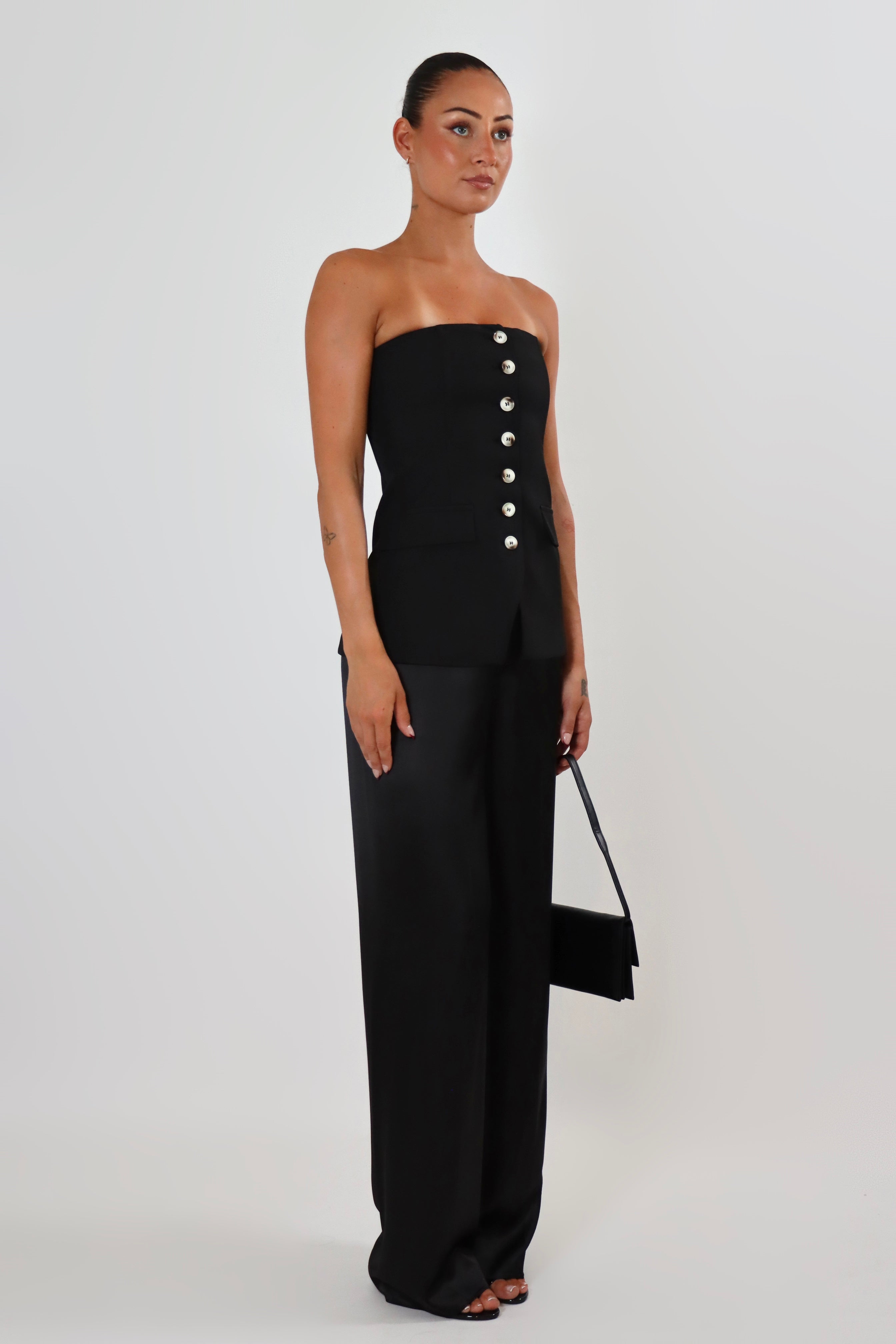 April Seven strapless vest top in black – structured strapless silhouette with button closure and flap pockets.