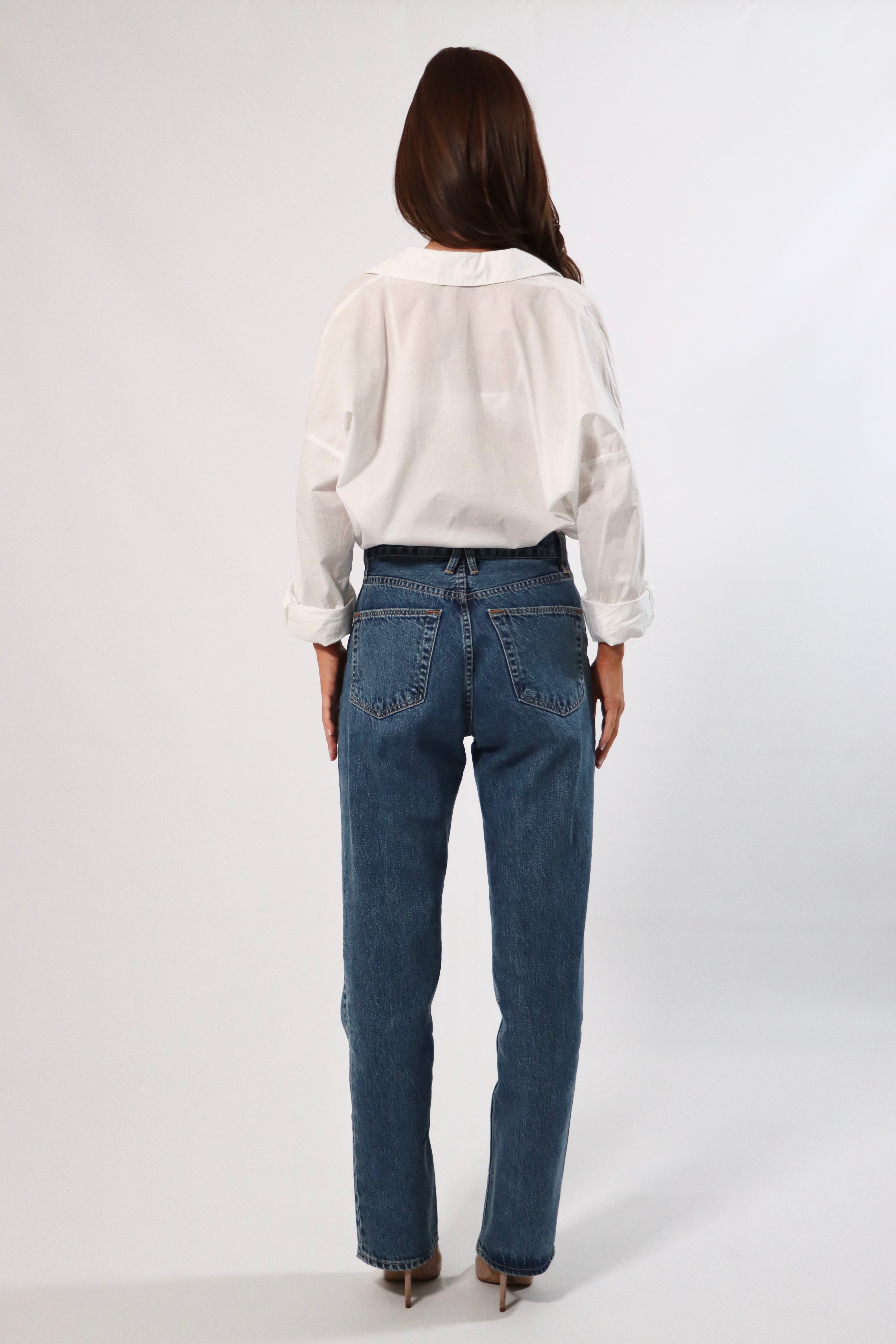 Back view of woman in white oversized cotton shirt and blue jeans.