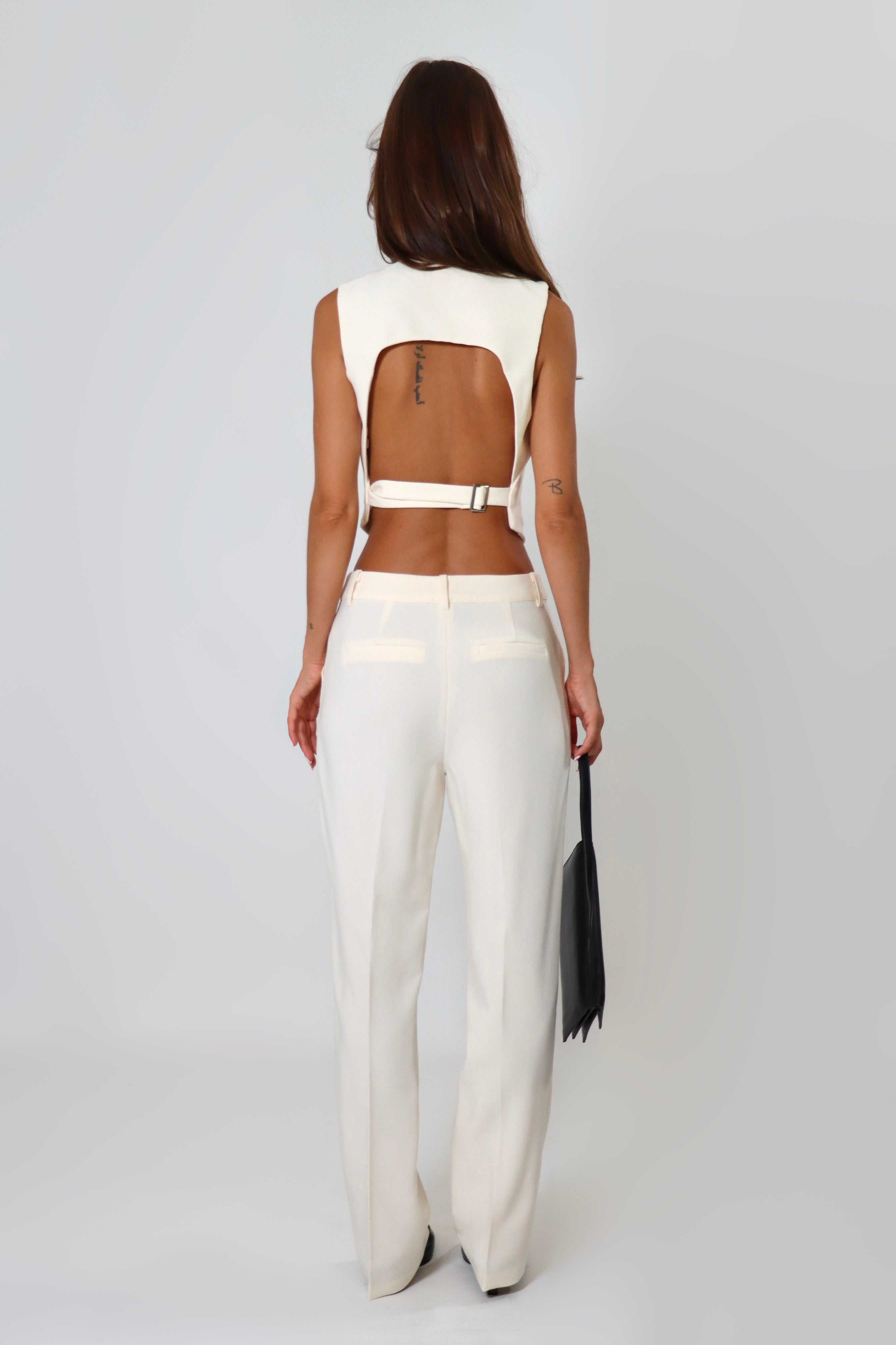 April Seven cropped backless vest and straight-leg pant set in white – minimalist tailored two-piece with clasp-back vest.