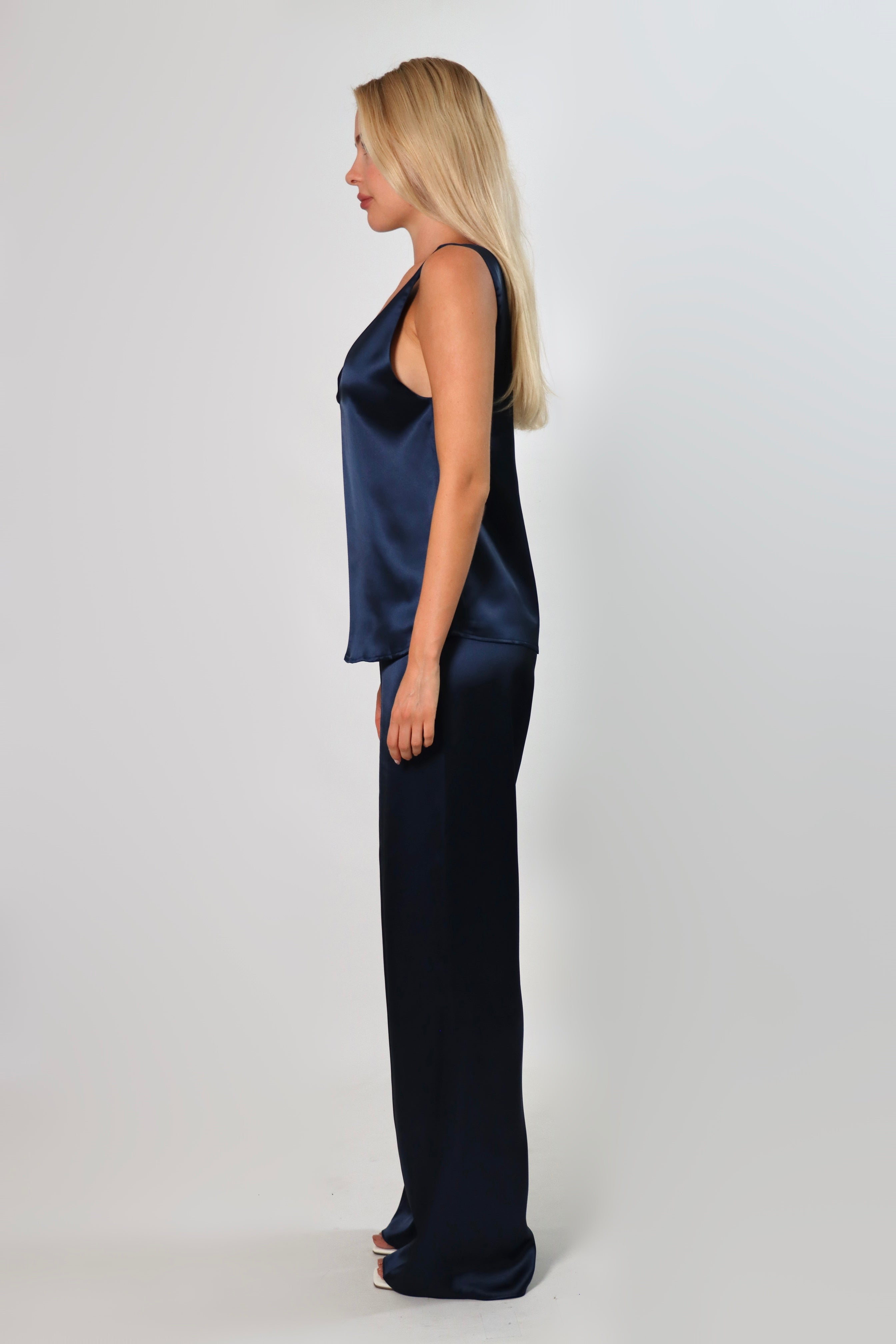 Model wearing a navy satin sleeveless top with a deep plunging neckline and relaxed fit, styled with matching satin pants against a neutral background.