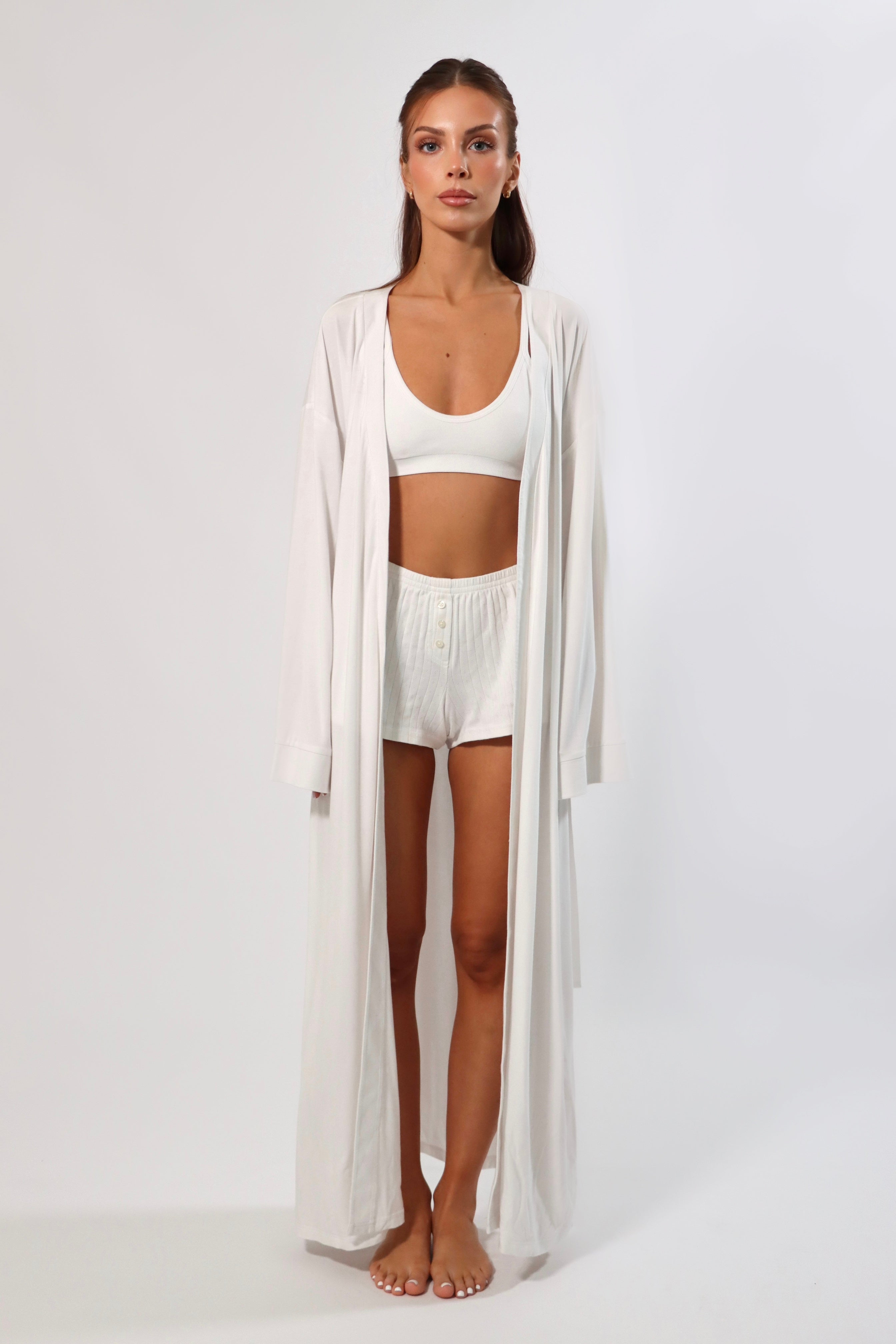 Woman in white maxi robe with bell sleeves, bralette, and ribbed shorts. Loungewear set.