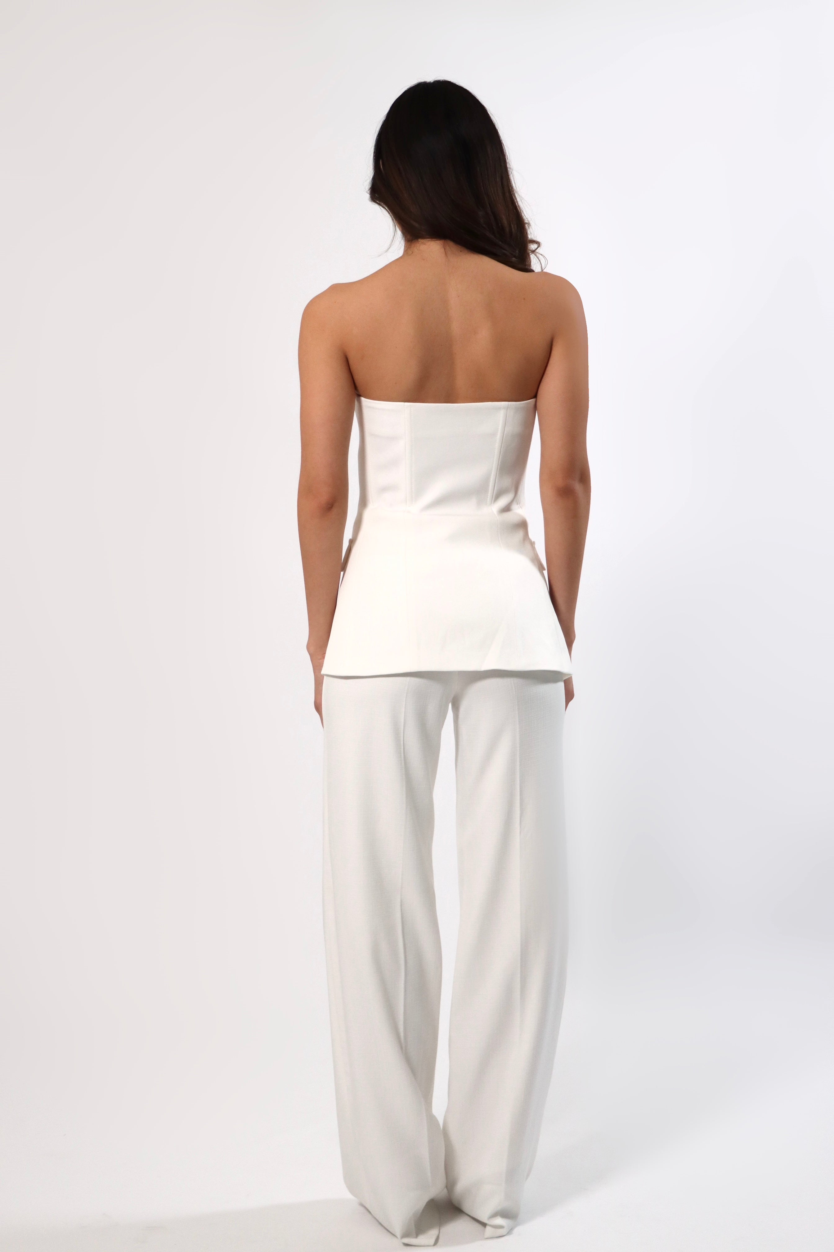 Back view of woman in a white strapless vest top and wide-leg trousers.