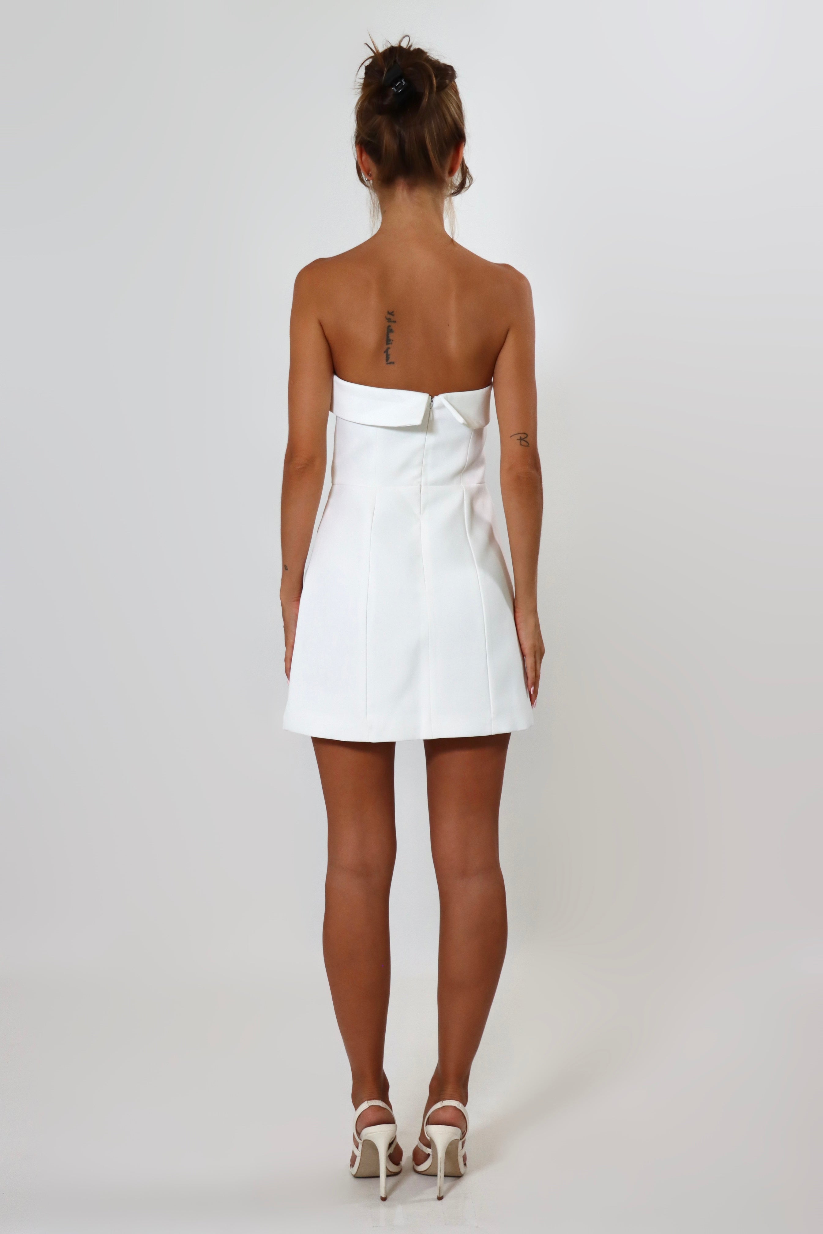 April Seven Kara Dress in white – strapless fitted mini dress with welt pocket detail, structured fabric, and full lining.