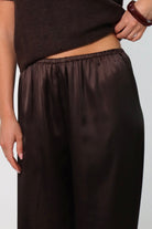 Elegant mid-waist wide-leg satin pants in a rich espresso brown shade, featuring a smooth, glossy finish and a fluid drape for a sophisticated, effortless look.