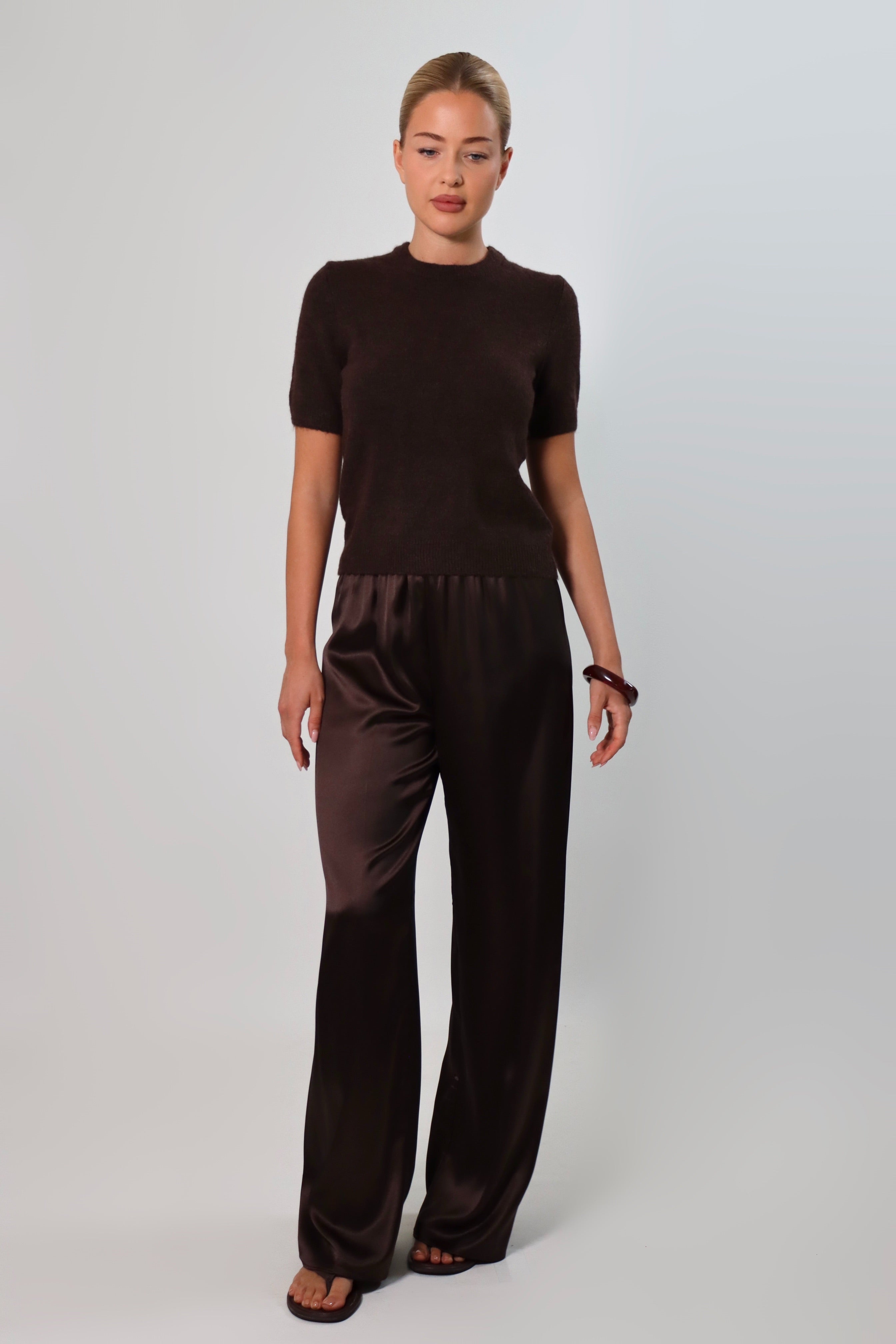 Elegant mid-waist wide-leg satin pants in a rich espresso brown shade, featuring a smooth, glossy finish and a fluid drape for a sophisticated, effortless look.