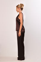 Model wearing a brown satin sleeveless top with a deep plunging neckline and matching satin pants for a sleek monochrome look.