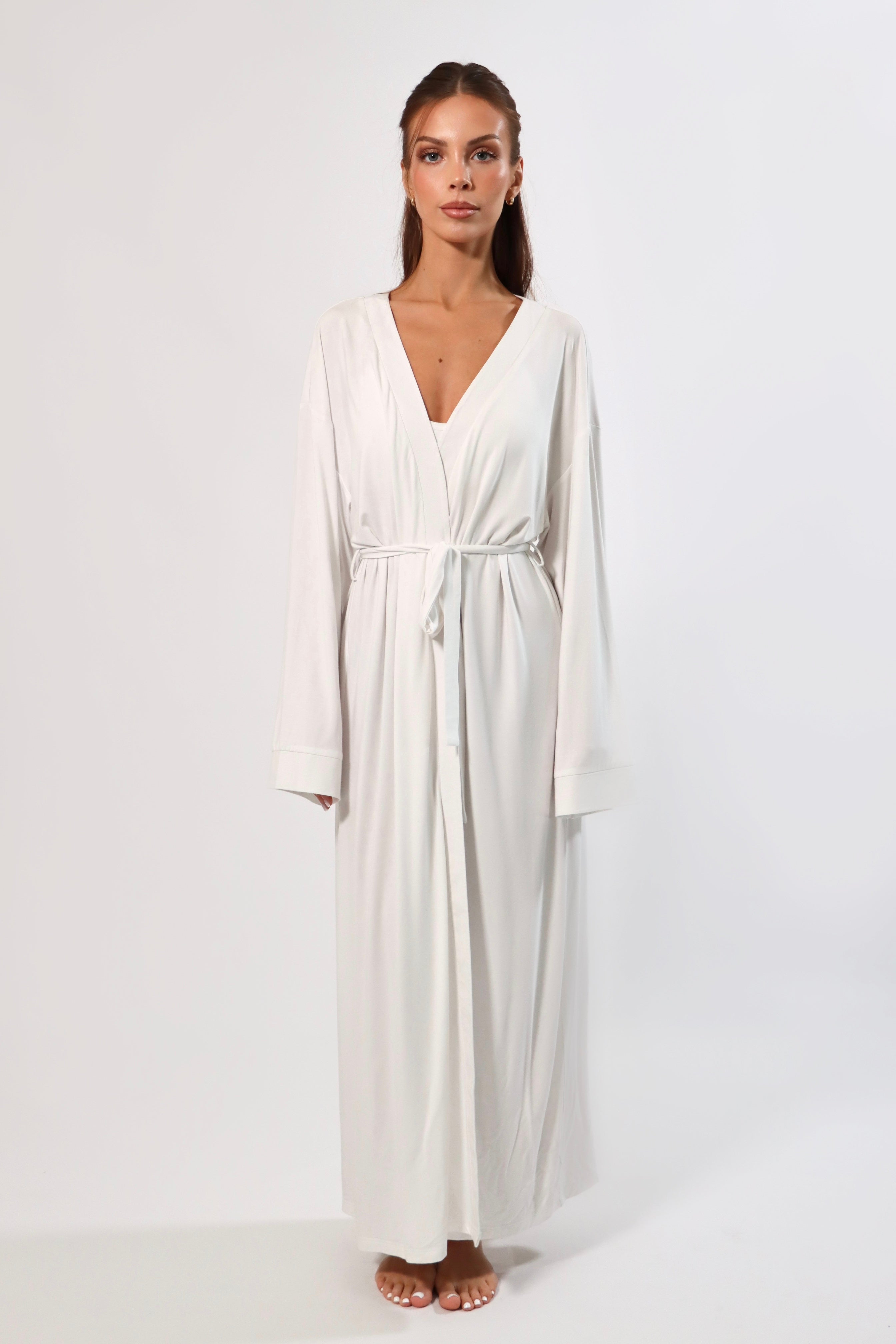 Woman in a long white robe with bell sleeves and tie waist.