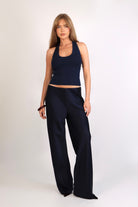 A woman wearing the Freya Tank, featuring a deep scoop neckline and a fitted racerback silhouette. The image highlights the fine rib fabrication and the body-skimming fit of the top in a neutral setting.