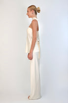 A model wearing a cream-colored, strapless satin top with a matching scarf wrapped elegantly around her neck. The top has a clean, structured bodice and is paired with matching April Satin Pants for a monochromatic, sophisticated look against a plain white background.