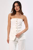 Woman in a white strapless vest top with button front and faux pockets.