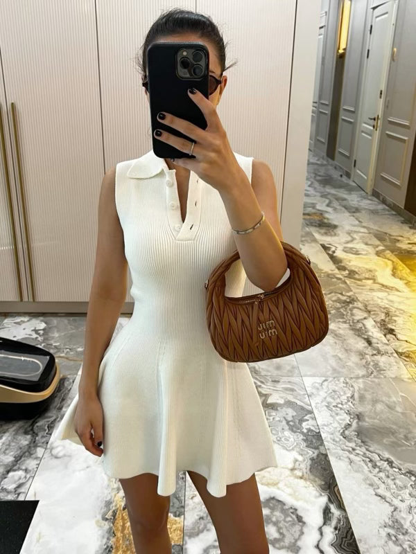 Woman in white sleeveless knit mini dress with collar and brown Miu Miu handbag.