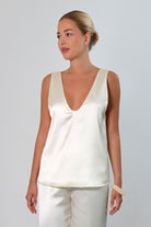 Ivory: Model wearing an ivory satin sleeveless top with a deep plunging neckline and matching satin pants against a neutral background.