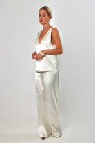 Ivory: Model wearing an ivory satin sleeveless top with a deep plunging neckline and matching satin pants against a neutral background.